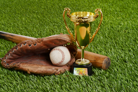 Baseball glove, baseball, and baseball trophy on a baseball outfield