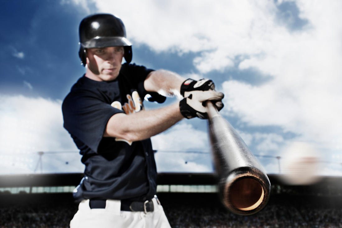 Baseball player performing baseball drills with his baseball bat while in full baseball uniform on a party cloudy day