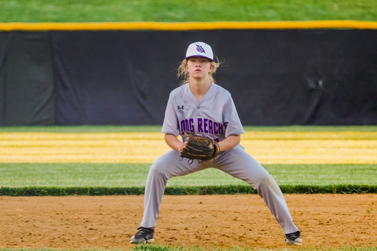 Baseball player performing fielding baseball drills in full baseball uniform on a baseball diamond