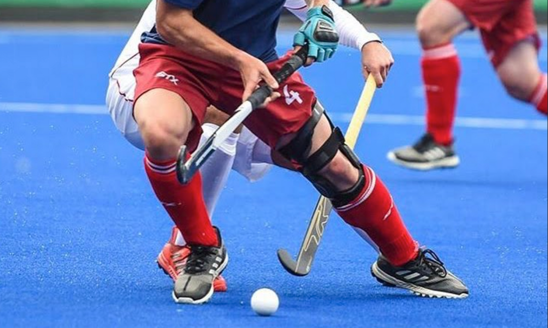 black field hockey grip during field hockey game player in red shinguards playing offense