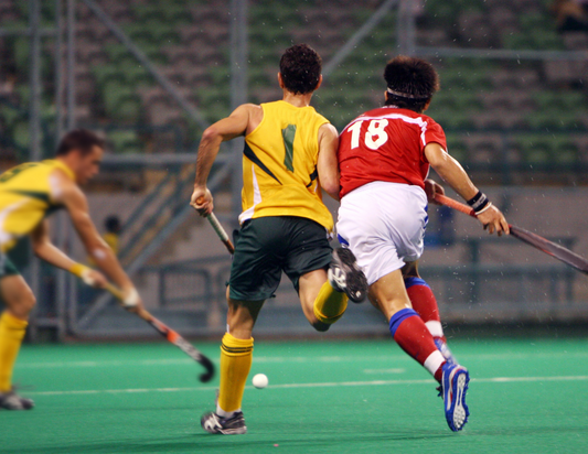 Field hockey players advancing the ball down the field, hitting the ball with their field hockey stick that is wrapped in field hockey grip tape while wearing cleats and shin guards and having fun playing field hockey