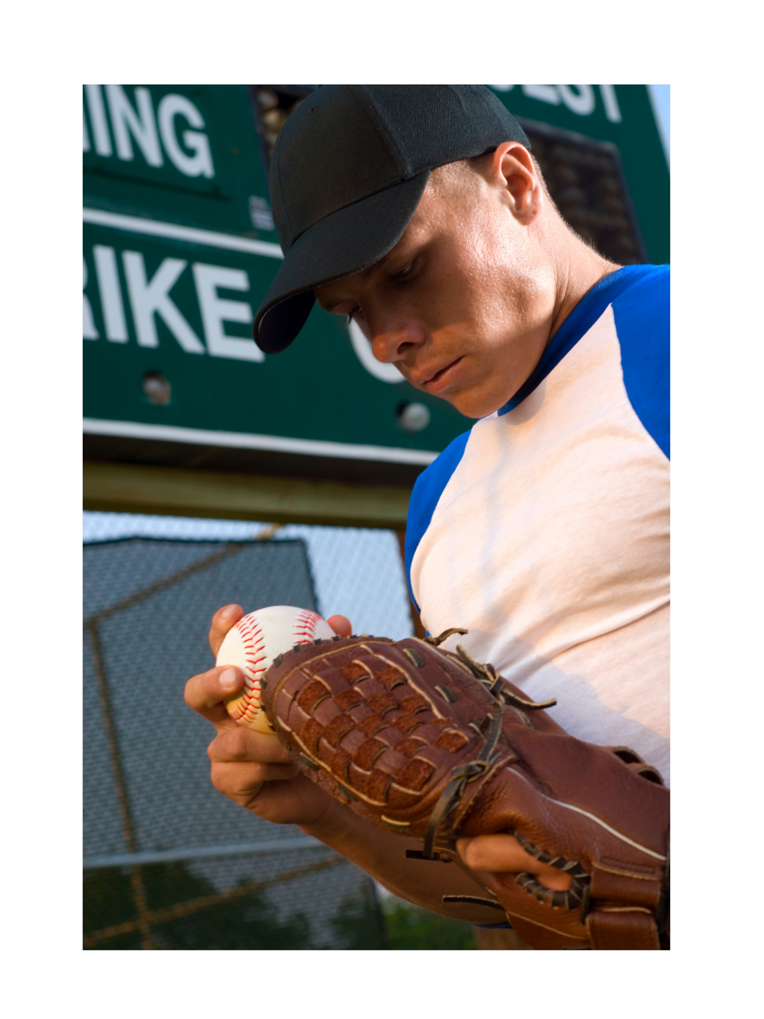 Baseball player holding a baseball and baseball glove in a baseball uniform at a baseball field